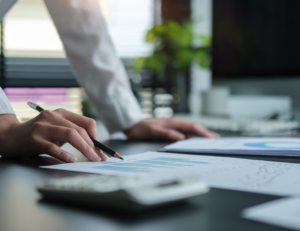 Hand die schrijft op financiële documenten op een bureau