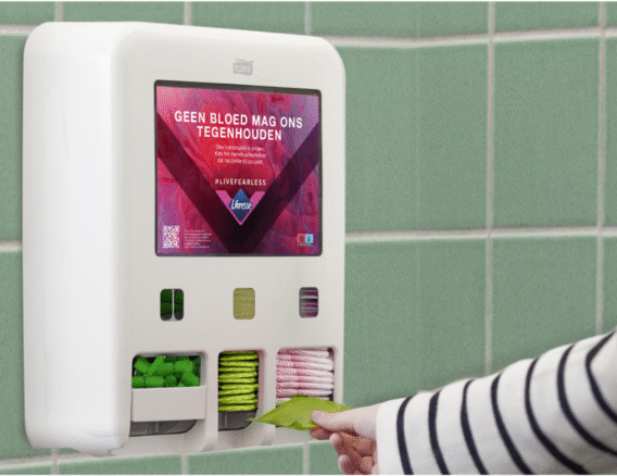 Dameshygiene op toilet een menstruatiedispenservan Tork waar een hand een inlegkruisje pakt