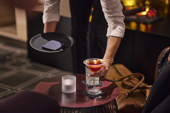 Ober brengt een cocktail in restaurantsetting met Bio Dunisoft servetten op het dienblad