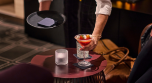 Ober die een cocktail plaatst op een servet op tafel