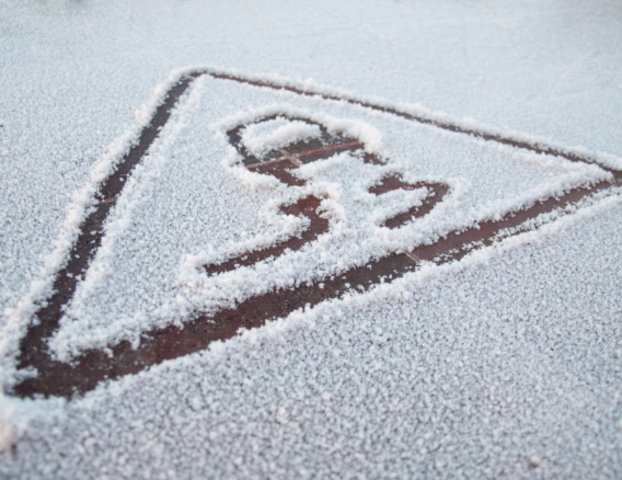 laag sneeuw op wegdek met attentie teken van gladheid